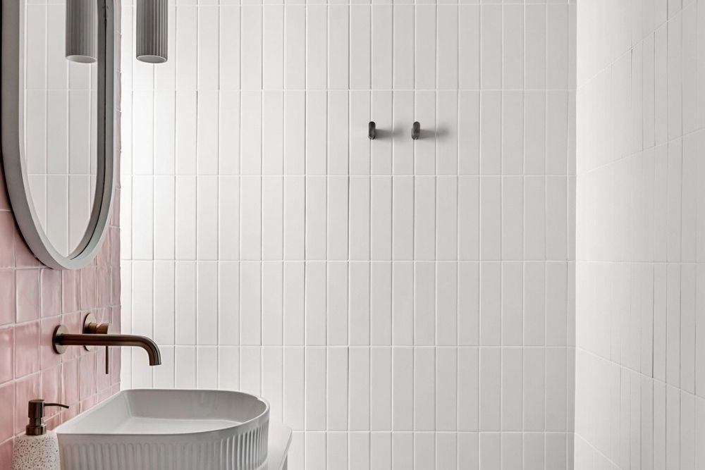 Modern pink tiled bathroom with a sleek white basin and a contemporary matte black tap-